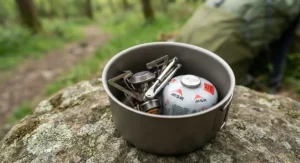A tiny ultralight gas stove packed inside a small cooking pot, demonstrating its minimal size for lightweight hiking.