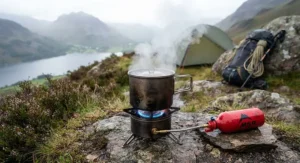 An efficient multi-fuel stove for expedition camping boiling water in a titanium pot during a remote wild camping excursion in the Lake District.