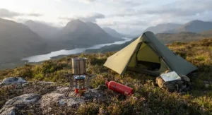 A lit petrol camping stove outside a small green tent, set against the dramatic scenery of the Scottish Highlands.