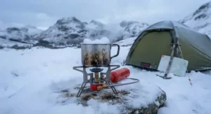 A highly reliable petrol camping stove melting snow in a billy can during a freezing winter wild camping trip in the Lake District.