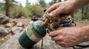Checking valve fitting on butane canisters for camping stove before cooking in the Lake District