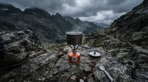 A backpacker cooking warm soup with camping gas for cold weather during a damp and chilly autumn hike in the Lake District